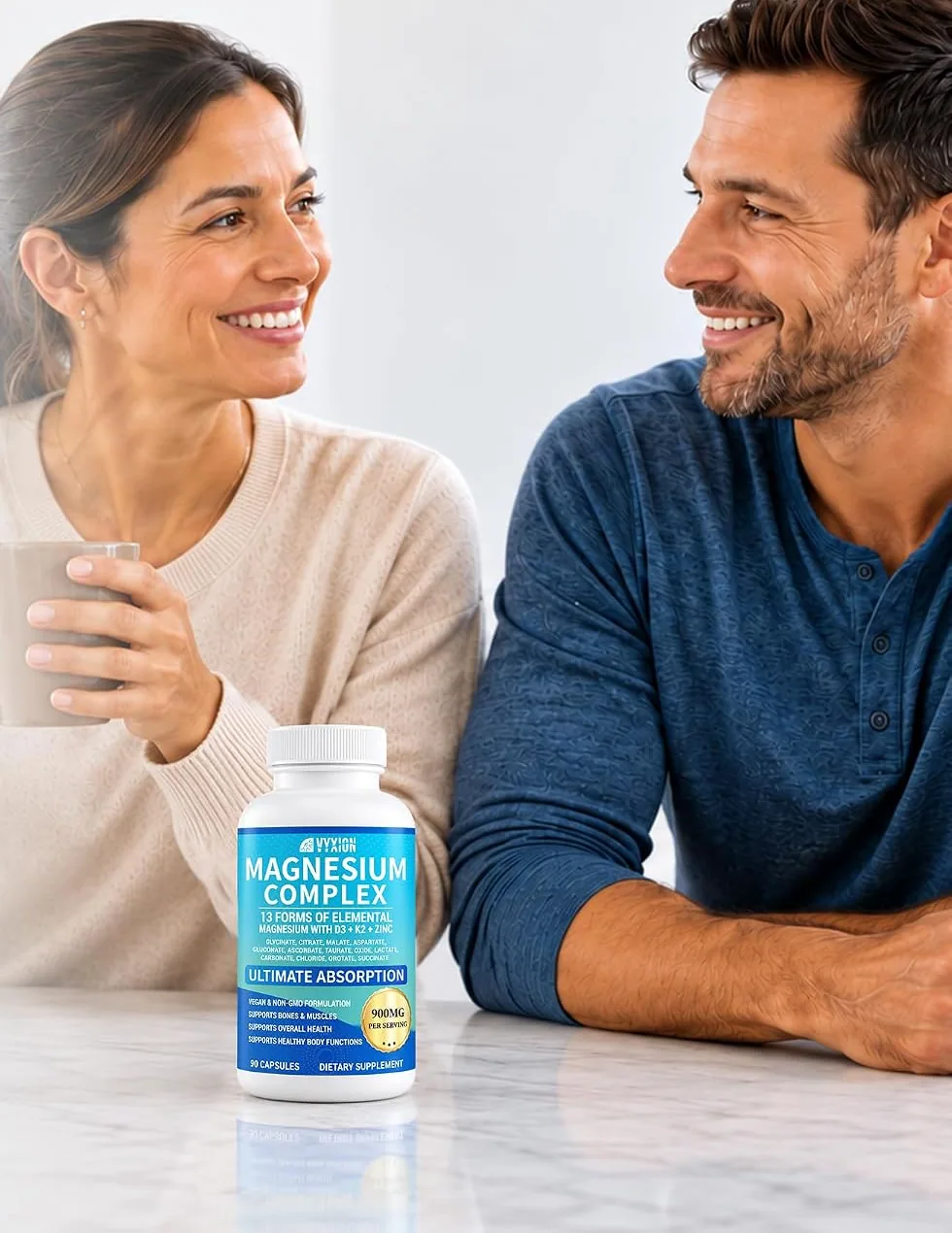 A woman and a man with mugs at a kitchen counter, a bottle of Vyxion Magnesium Complex in front of them
